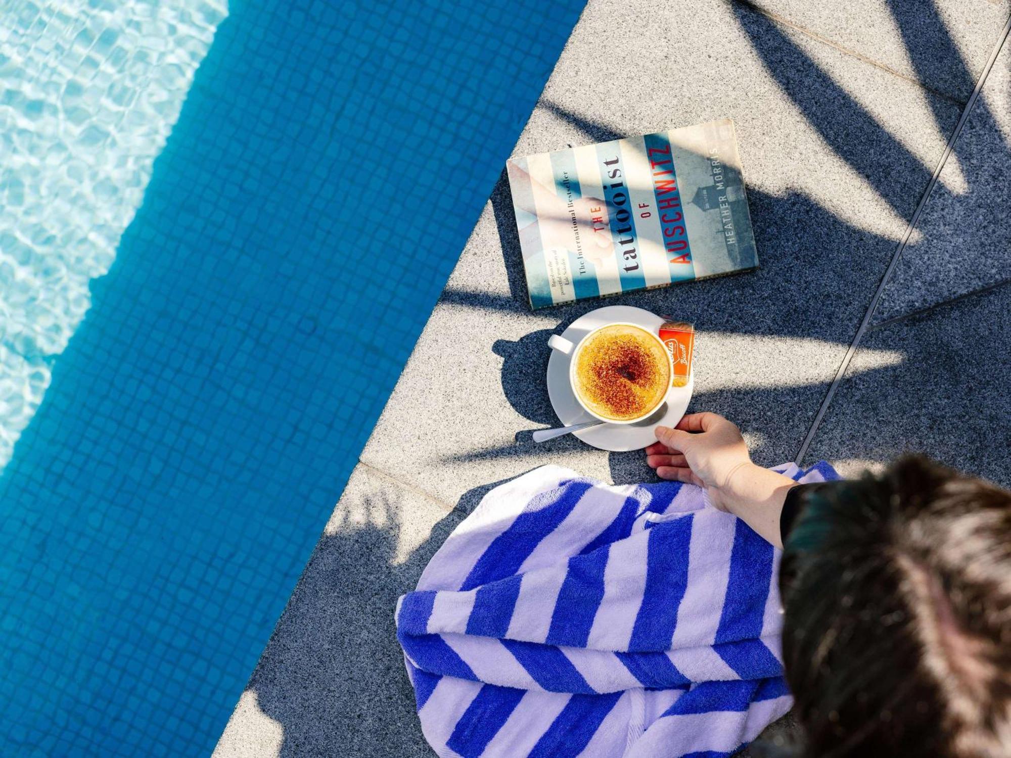 Отель Pullman Brisbane Airport Экстерьер фото A woman reading a book by the pool